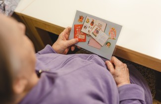 Henkilö katsoo kiiltokuvakorttia.