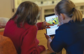 Sote-ammattilainen opastaa tablettilaitteen käytössä.