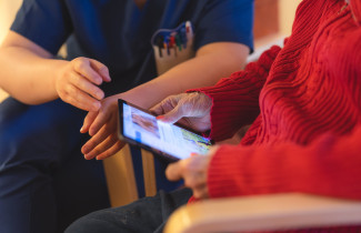 Ikääntynyt henkilö kädessään tablettilaite.