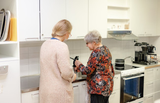 Kaksi henkilöä keittiössä keittämässä kahvia.