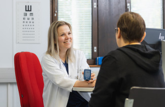 Lääkäri mittaa asiakkaan verensokerin.