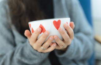 Nainen pitää kulhoa kädessään, jossa sydämen muotoisia kuvioita.