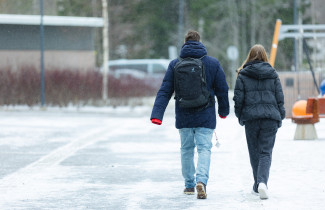 Kaksi henkilöä kävelevät pihalla.