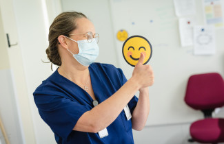 Ammattilainen näyttää peukkuja ja hymyilevaa kuva-emojia.