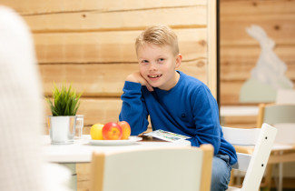 Lapsi lukee lehteä hedelmäkulhon vieressä.