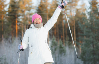 Sauvakävelevä henkilö hurraa lumisessa maisemassa.