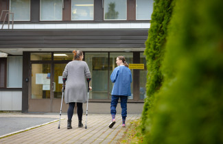 Asiakas ja ammattilainen kävelevät terveysasemalle.