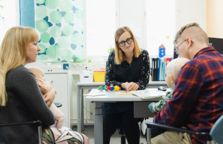 Lapsiperhe juttelee neuvolassa terveydenhoitajan kanssa.