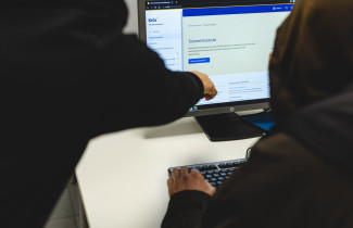 Sosiaaliohjaaja opastaa asiakasta löytämään tietoa verkkosivuilta.