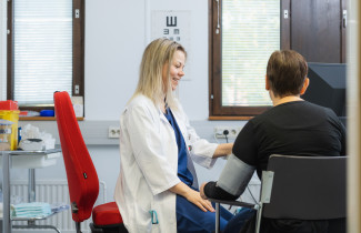 Lääkäri mittaa verenpaineen asiakkaalta.