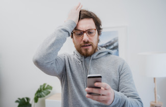 Ärsyyntynyt mies katsoo puhelintaan.