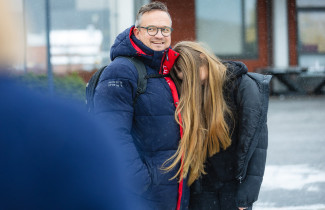 Aikuinen ja nuori seisomassa vierekkäin ulkona.
