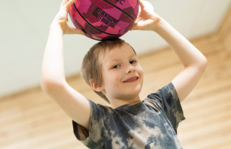 Lapsi pitää punaista palloa päänsä päällä.