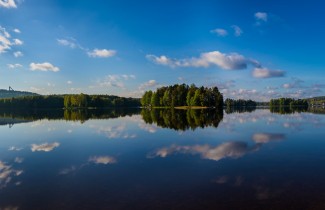 Keskisuomalainen järvimaisema, tyyni järvi, veteen heijastuva taivas ja saari