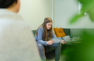 Nuori istuu sohvalla ja tutkii kortteja.