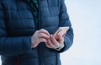 Mies tarkistaa puhelimella pankkitilinsä saldoa