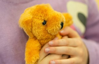 Lapsi pitämässä nallea sylissään.