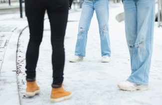 Kolme nuorta seisoo ulkona vastatusten, kuvassa näkyvissä vain kehon alaosa