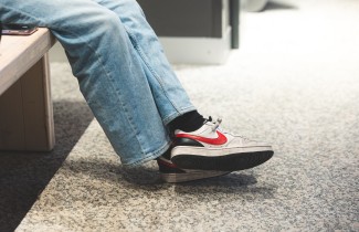 Nuori istuu penkillä lenkkarit jalassa.