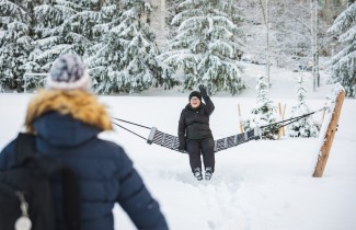 Iäkkäämpi henkilö riippukeinussa tervehtii tuttua tulijaa