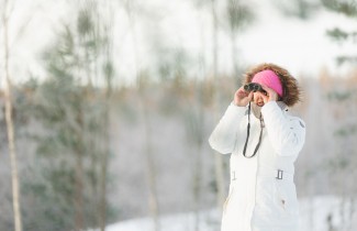 Nainen tähystää kiikareilla talvisäässä.