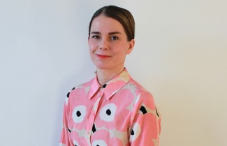 Henkilö seisoo kasvot kohti kameraa hymyillen.