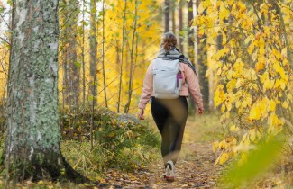 Ihminen kävelee reppu selässään syksyisessä metsässä.