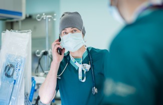 Leikkaava kirurgi puhuu puhelimeen leikkaussalissa