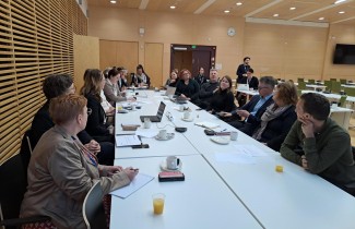 Ihmisiä istuu pitkän pöydän ääressä vastatusten.