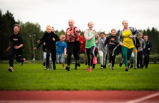 Iloisia lapsia urheilukentällä.