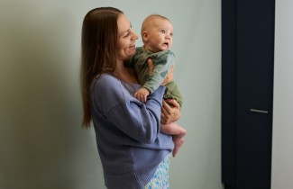 Vanhempi lapsi sylissään.