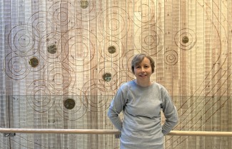 Kliinisen hoitotyön asiantuntija Anne Kanerva nojaa hymyillen puiseen kaiteeseen Sairaala Novassa.