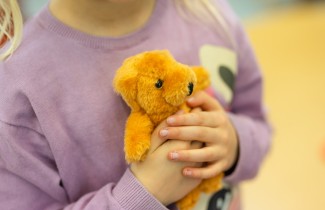 Lapsi pitää käsissään nallea