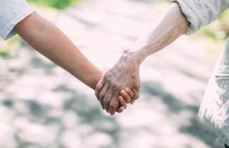 Kaksi ihmistä pitävät toisiaan kädestä kiinni.