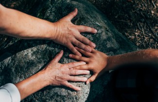 Ihmisten kädet luonnon kivillä.