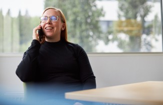 Iloinen ihminen puhelimessa.