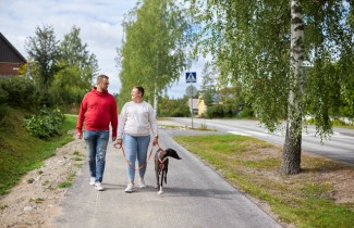 Aikuiset ja koira lenkkeilevät kesäisessä Keski-Suomessa.