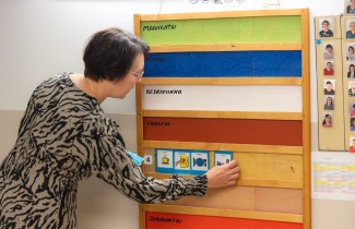 Päivätoiminnan ohjaaja laittaa taululle päivän ohjelman kuvien avulla.