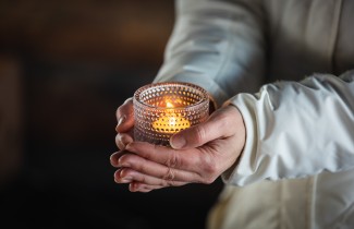 Henkilö kannattelee tuikkukynttilää käsissään. 