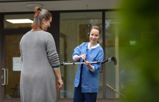 Keski-Suomen hyvinvointialueen ammattilainen auttaa asiakasta kävelysauvojen kanssa.