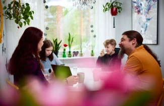 Perhe kotona ruokapöydän ääressä