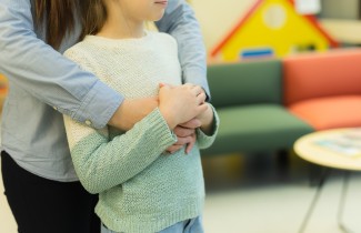 Lapsi aikuisen halauksessa