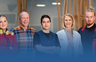 Hyvinvointialueen ammattilaisia seisoo rivissä ja katsoo hymyillen kameraan.