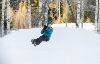 Henkilö keinuu keinussa talvella.