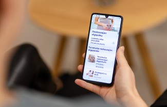 Henkilö pitää kädessään älypuhelinta, jossa näkyy digipolku