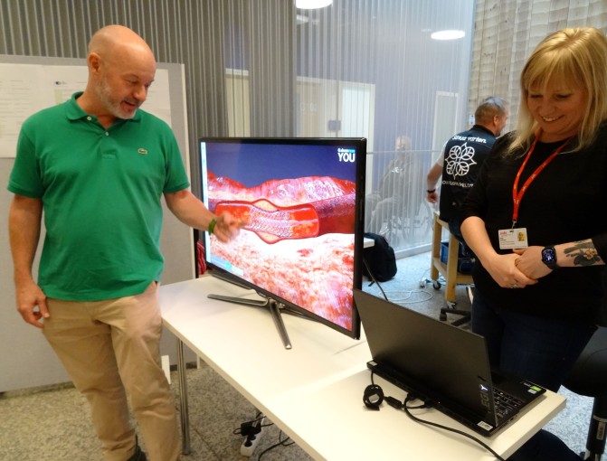 Riku Kaukonen näyttää ohjelmiston avulla, miten pallolaajennus tehdään suonen sisään. Lehtori Milja Forsman hymyilee vieressä.