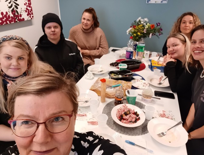 Ihmisiä yhteiskuvassa ruokapöydässä.