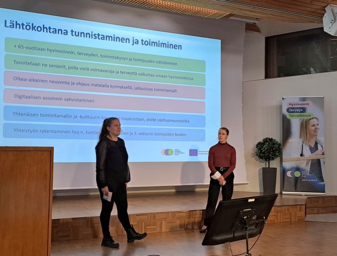 Kaksi puhujaa seminaarilavalla.