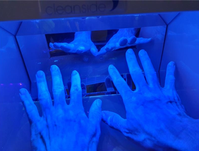 Sinivalolaatikossa on kaksi kättä, joissa näkyy vaalealla kohdat, mihin huuhde on yltänyt ja tummalla ne paikat, joissa sitä ei ole.