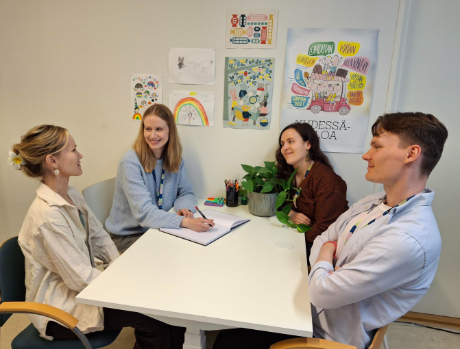 Neljä psykologia kokoontuneena istumaan pöydän ääreen.